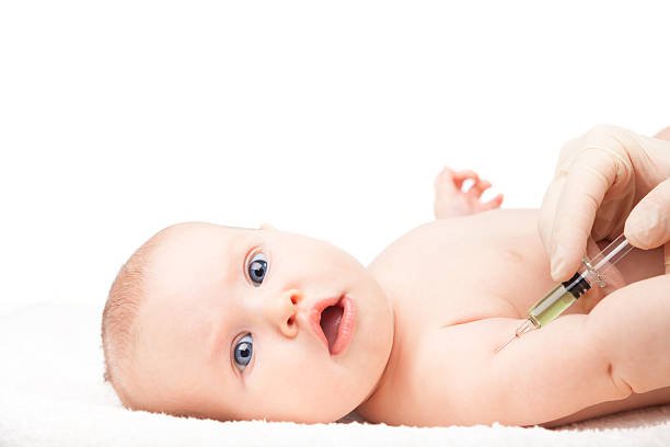 Child Vaccinations Pediatrician giving a three month baby girl intramuscular injection in arm. Child looking anxiously at a camera. Isolated on white background.